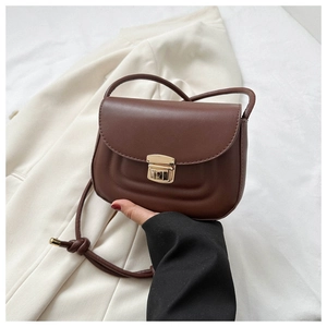 Close-up of a brown leather crossbody bag with wave stitching and a gold square clasp lock