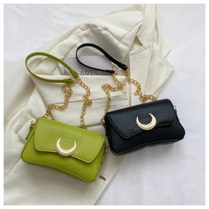 Close-up of crescent metal clasp on snakeskin textured green and black shoulder bags