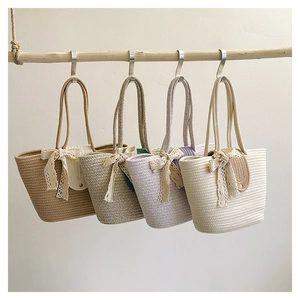 Detail of woven straw tote bags in four colors with delicate lace bows and long straps