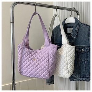 Detailed shot of quilted tote bags in lavender and pearl white with clover metal logo