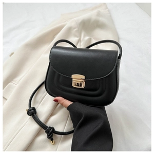 Close-up of minimalist black leather crossbody bag with wave texture and gold buckle