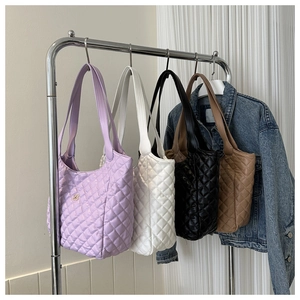 Quilted tote bags in lilac, white, black and brown colors hanging on a display