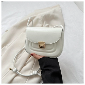 Detail of white PU leather crossbody bag with curved embossing and gold metal lock clasp