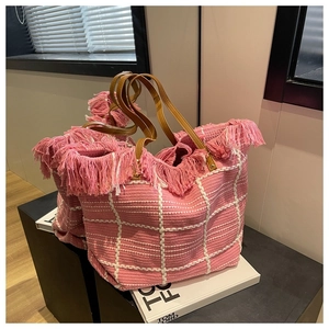 Detailed close-up of pink woven tote bag featuring fringe accents and leather straps