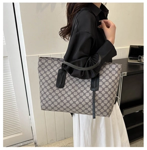 Detailed view of grey pattern tote bag with black leather handles on female model shoulder