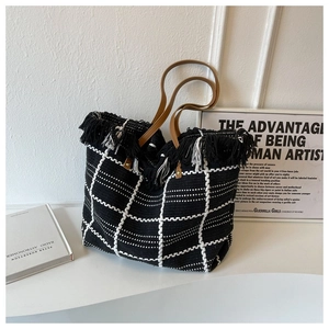 Detail view of knit tote bag featuring black and white grid pattern and fringe tassels