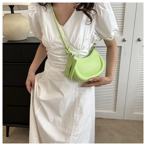 Detail of light green crescent underarm bag with small detachable pouch on a shoulder strap