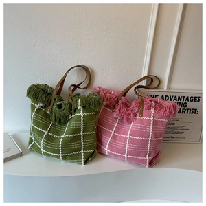Detail of woven tote bag showing pink and green knit texture with stylish fringe accents