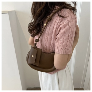 Close-up of brown faux leather crescent shoulder bag with knot detail and mini pouch