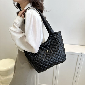 Quilted black tote bag with gold floral accent and wide strap for casual commuting