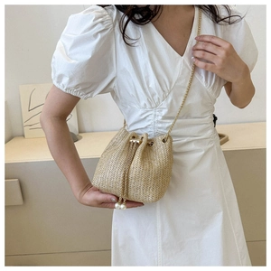 Vue détaillée du sac seau en paille tressée avec chaîne dorée et glands en perles
