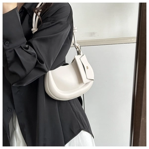 Detailed side view of a cream-colored minimalist underarm bag with a mini pouch charm