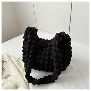 Detail showing unique black popcorn bubble texture on fashion pleated handbag surface