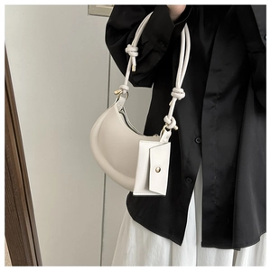 Detail of white half-moon underarm bag with knot strap and detachable small card pouch