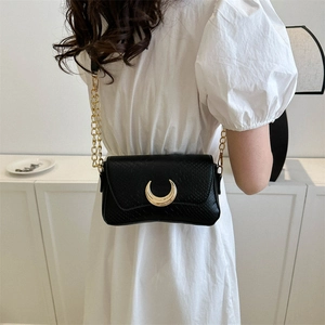 Chic black crescent moon shoulder bag with gold chain and crocodile texture on modern model