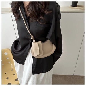 Beige crescent crossbody bag with mini pouch shown on model in stylish modern setting