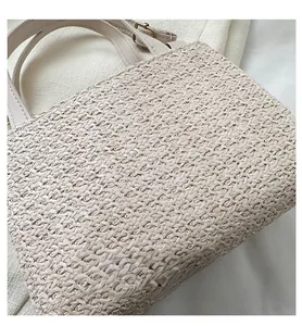 Close-up of a cream woven straw handbag featuring detailed texture and a synthetic leather strap