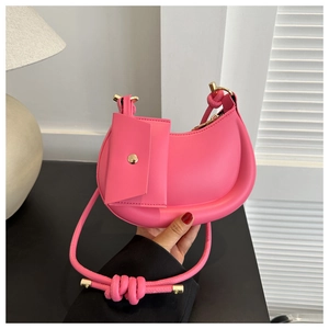 Close-up of pink crescent underarm bag with unique rope knot strap and small coin purse