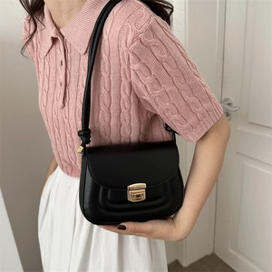 Minimalist black square crossbody bag with gold clasp shown on model with pink knitwear