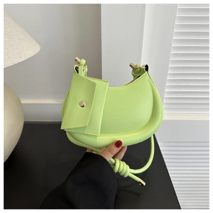 Detail of light green crescent underarm bag with gold hardware and knot strap