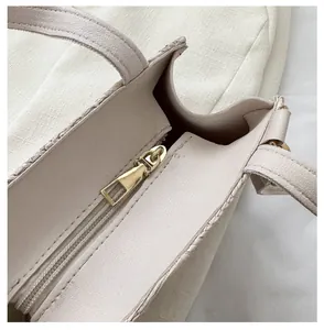 Detail of premium gold metal zipper and smooth leather texture on a beige crossbody bag