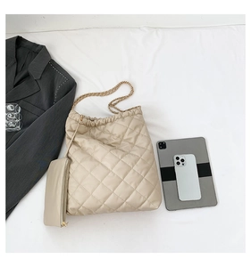 Gros plan du sac cabas matelassé beige avec chaîne dorée et petite pochette