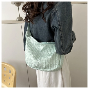 Close-up of mint green pleated shoulder bag with unique wavy texture on a model