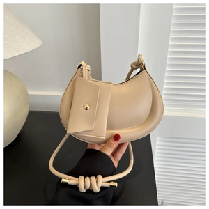 Detail of beige half-moon shoulder bag with knotted strap and small matching pouch