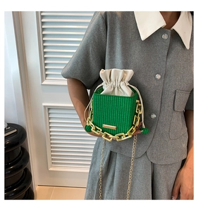 Close-up of bright green woven bucket bag with gold chain and drawstring liner