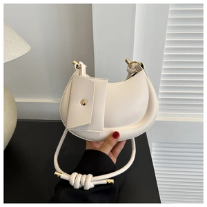 Close-up of a cream crescent hobo bag featuring a knotted handle and gold hardware