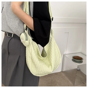 Detail of light green quilted hobo bag with mini coin purse attachment and fashion text