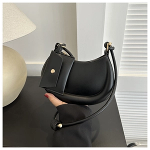 Detail of black crescent shoulder bag with round handle and hanging coin purse