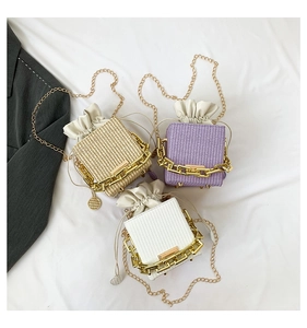 Close-up of woven mini square handbags with chunky gold chain handles in three colors