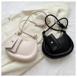Close-up of minimalist half-moon crossbody bags with a small envelope pouch and gold accents
