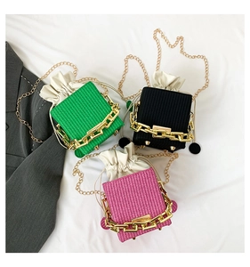 Detailed view of square woven drawstring bags in green, black and pink with gold chains