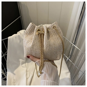 Détail du sac seau en paille tressée avec cordon chaîne dorée et pendentif perle