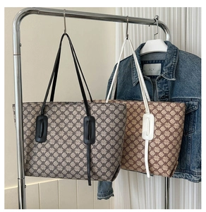 Close-up of geometric pattern canvas tote bags in black and brown hanging on a metal rack