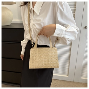 Detailed V-shaped weave texture on a natural straw tote bag with gold metal buckle