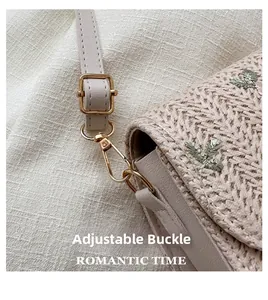 Detail of adjustable metal buckle and floral embroidery on woven beige shoulder bag