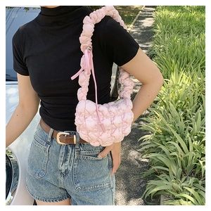Detailed close-up of pink quilted puffer shoulder bag with pleated ruffle strap and zipper