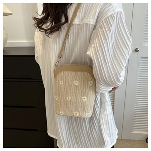 Détail du sac seau en paille d'été avec broderie marguerites et lanière en cuir