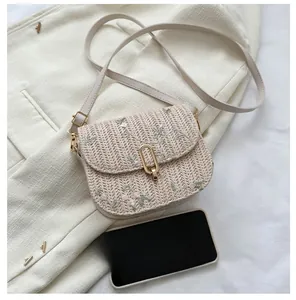 Macro shot of embroidered floral straw bag featuring a golden clasp and slim leather strap