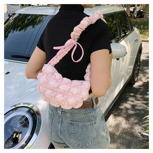 Detailed close-up of pink ruched crescent bag with quilted heart pattern and bow shoulder strap