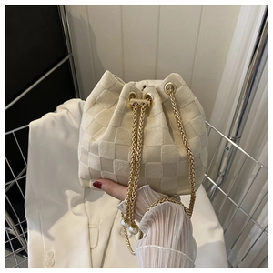 Détail du sac seau crème avec texture à carreaux et cordon en chaîne à perles