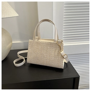 Detail showing the creamy white woven texture and golden hardware of the small square bag