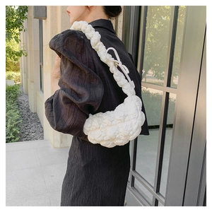 Detail of white quilted bubble fabric shoulder bag with ruffled strap and bow decoration