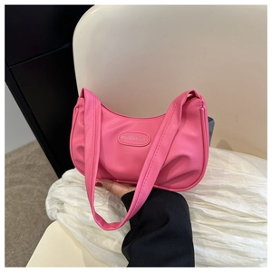 Dettaglio di una borsa a tracolla rosa con texture increspata e placca metallica