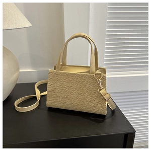 Detail of chevron woven straw bag with PU handles and golden metal hardware