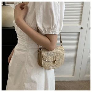 Detail of straw saddle bag with delicate floral embroidery and gold metal clasp