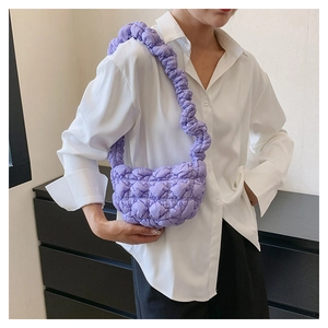 Close-up detail of the purple bubble quilted texture and pleated strap of the shoulder bag